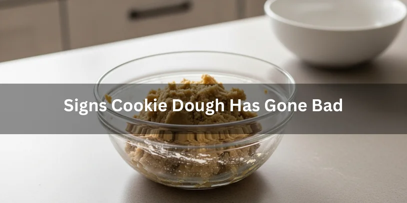 Homemade cookie dough in a glass bowl showing signs of spoilage such as discoloration and ingredient separation, photographed under soft natural lighting.-how long does homemade cookie dough last in the fridge 