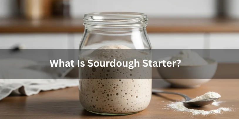 A glass jar of active sourdough starter with visible bubbles on a wooden countertop, illustrating what sourdough starter is.-difference between sourdough starter and discard 