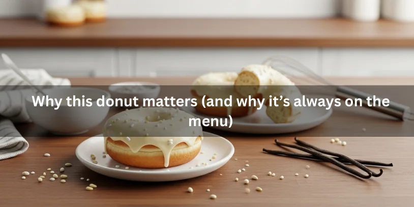 A perfectly frosted vanilla donut, partially sliced to show soft interior, with sprinkles and vanilla glaze nearby, emphasizing its appeal as a menu staple.-vanilla frosting donut 