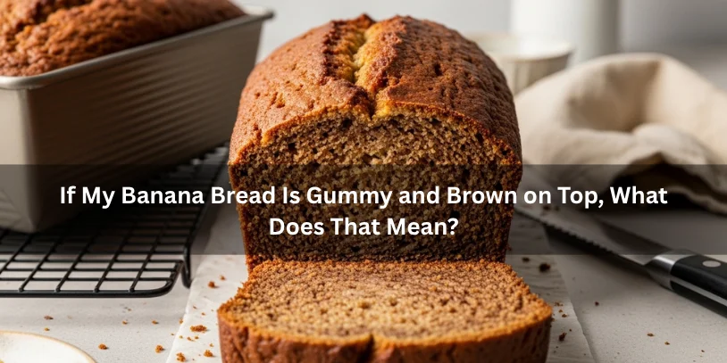 Banana bread with a browned top crust and a dense gummy center, illustrating a loaf that looks done outside but remains underbaked inside under soft natural lighting.-why is my banana bread gummy 